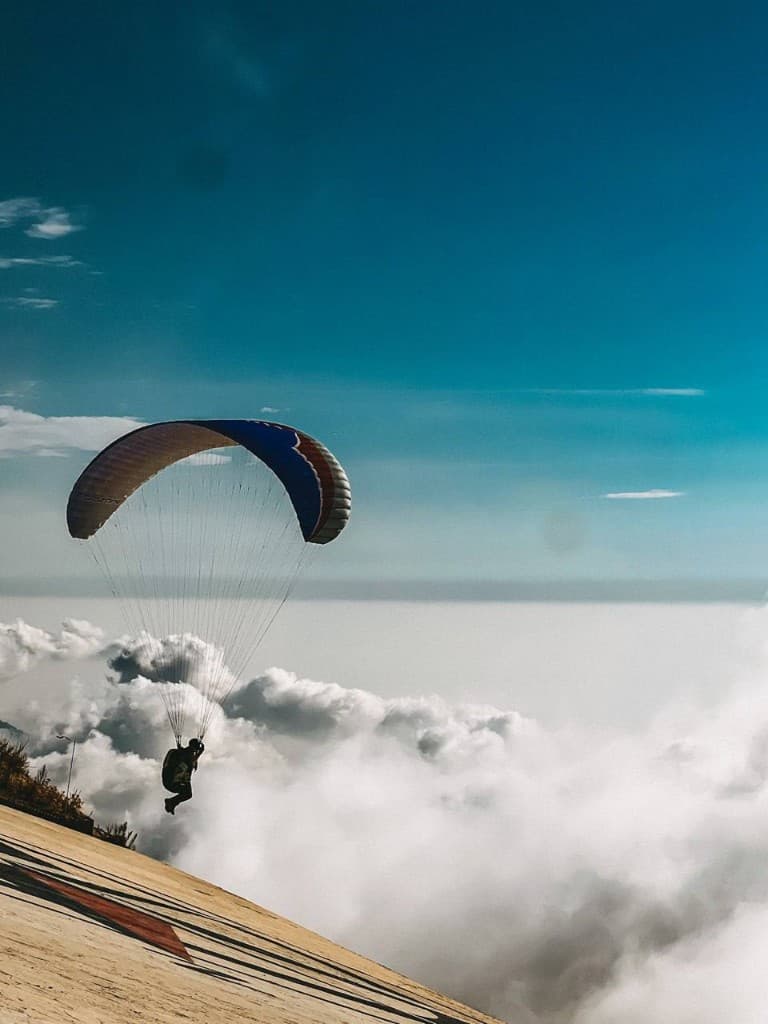 Paraglider gliding high above a sea of clouds