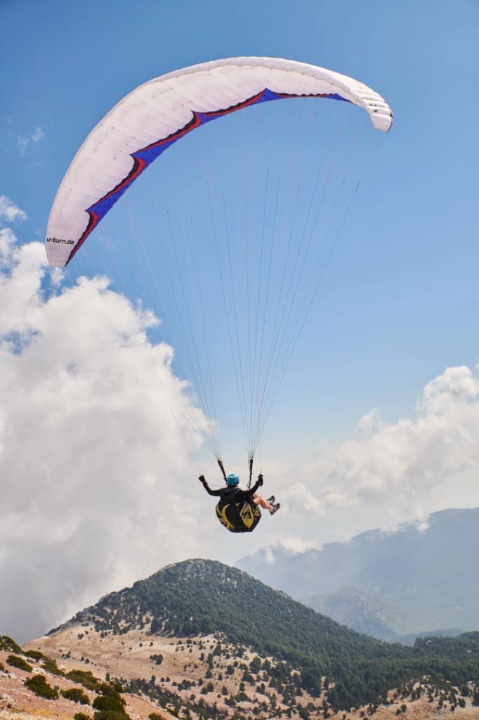 Pilot under a white wing over the mountains